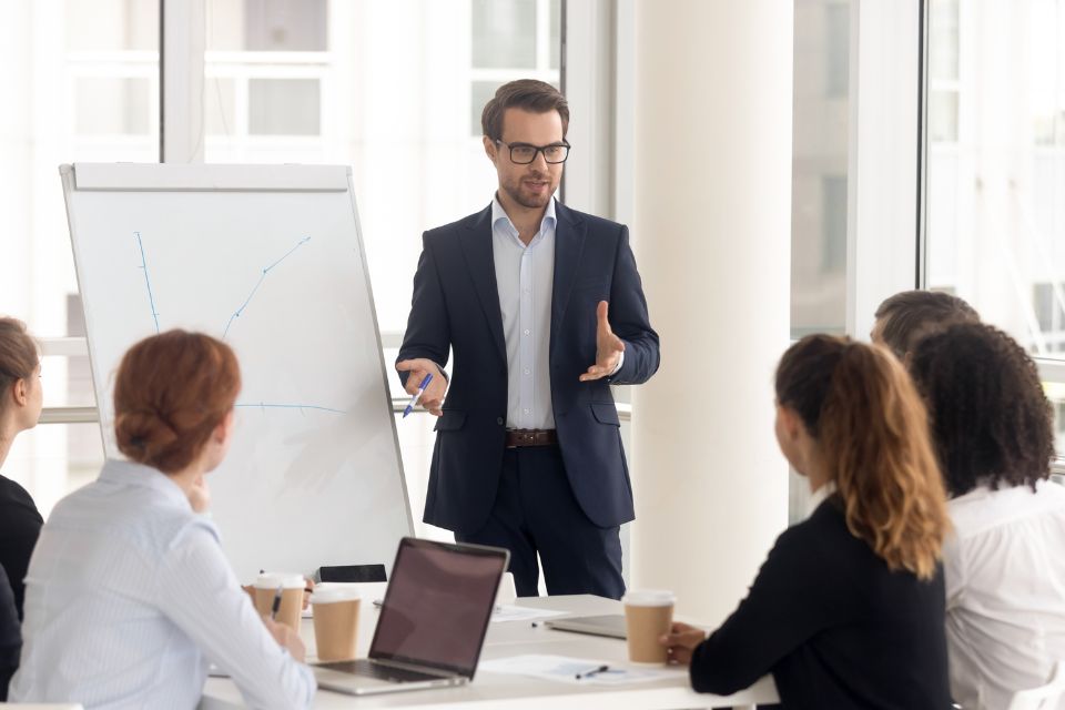 Leader asking better questions while presenting to a diverse team in a professional meeting room