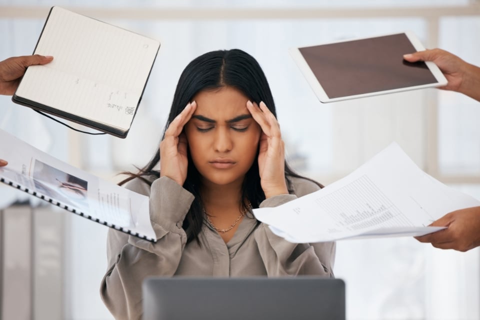 Weary professional resting their head on one hand at a desk beside a laptop, illustrating burnout recovery at work